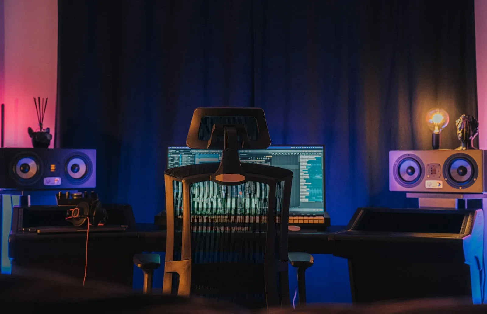 A dark home studio with monitor speakers and a DAW open on screen
